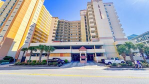 A hotel with multiple floors, a central entrance, and a parking area.