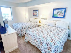 A hotel room with two beds, a desk, and a window. - Verandas 602 (North Myrtle Beach)