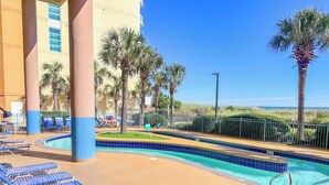 A pool area with lounge chairs, palm trees, and a view of the beach.