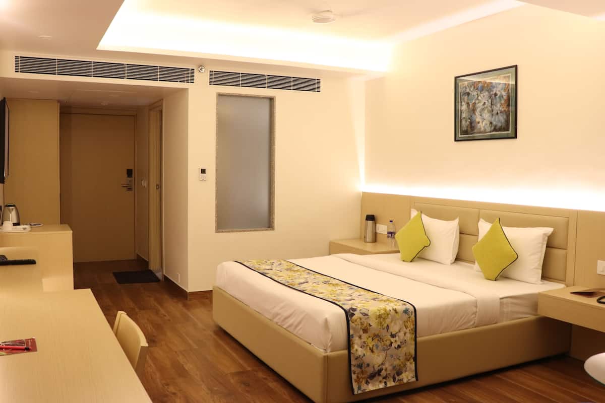A hotel room with a bed, bedside tables, a desk, and a chair.