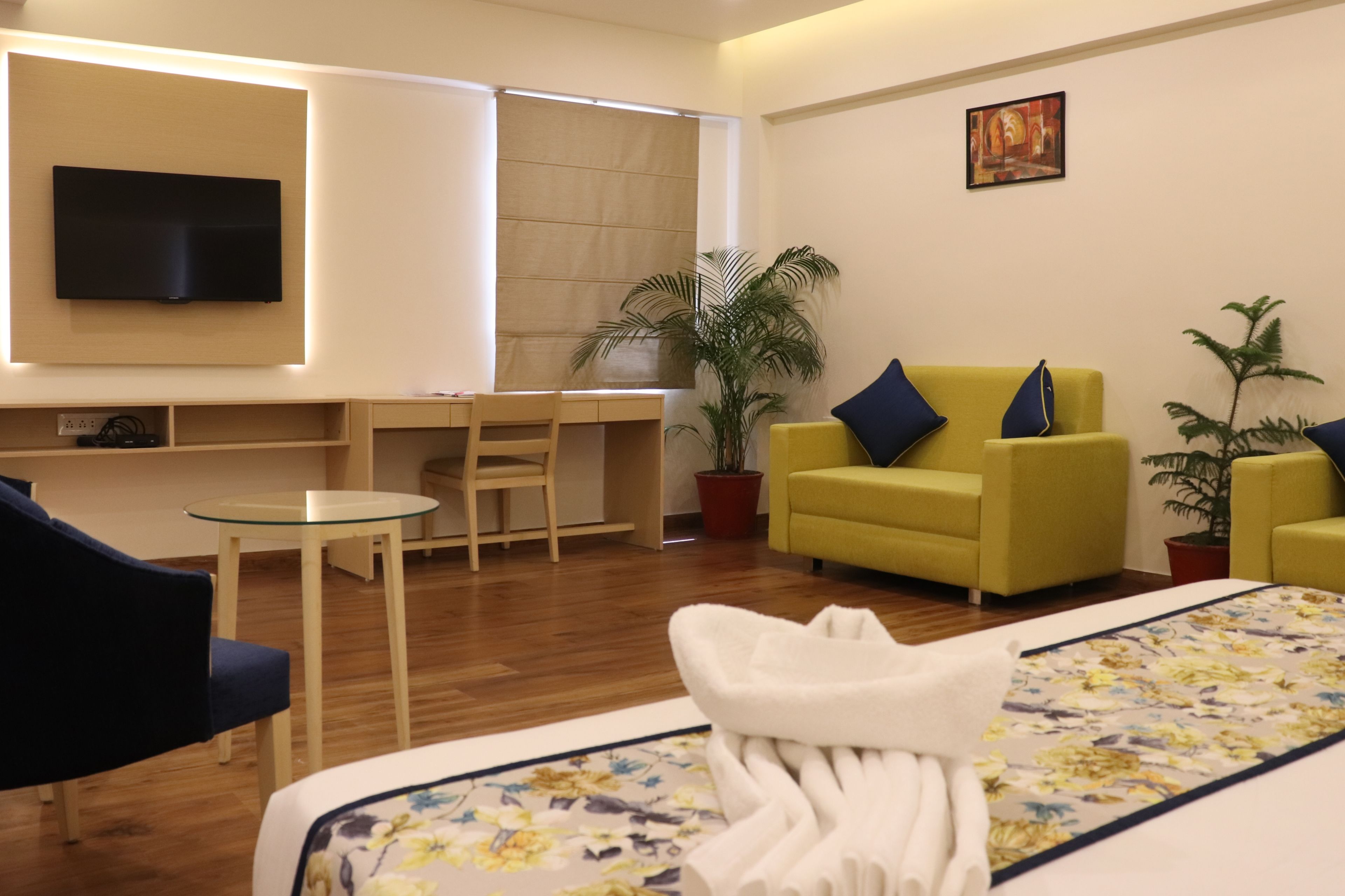 Una habitación de hotel con cama, escritorio, silla, sofá y televisor.
