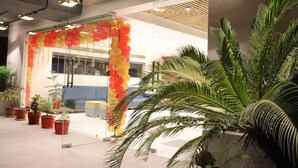 A modern interior with a glass door entrance, potted plants, and a ceiling with exposed pipes. - Hotel Le Amor (Kota)