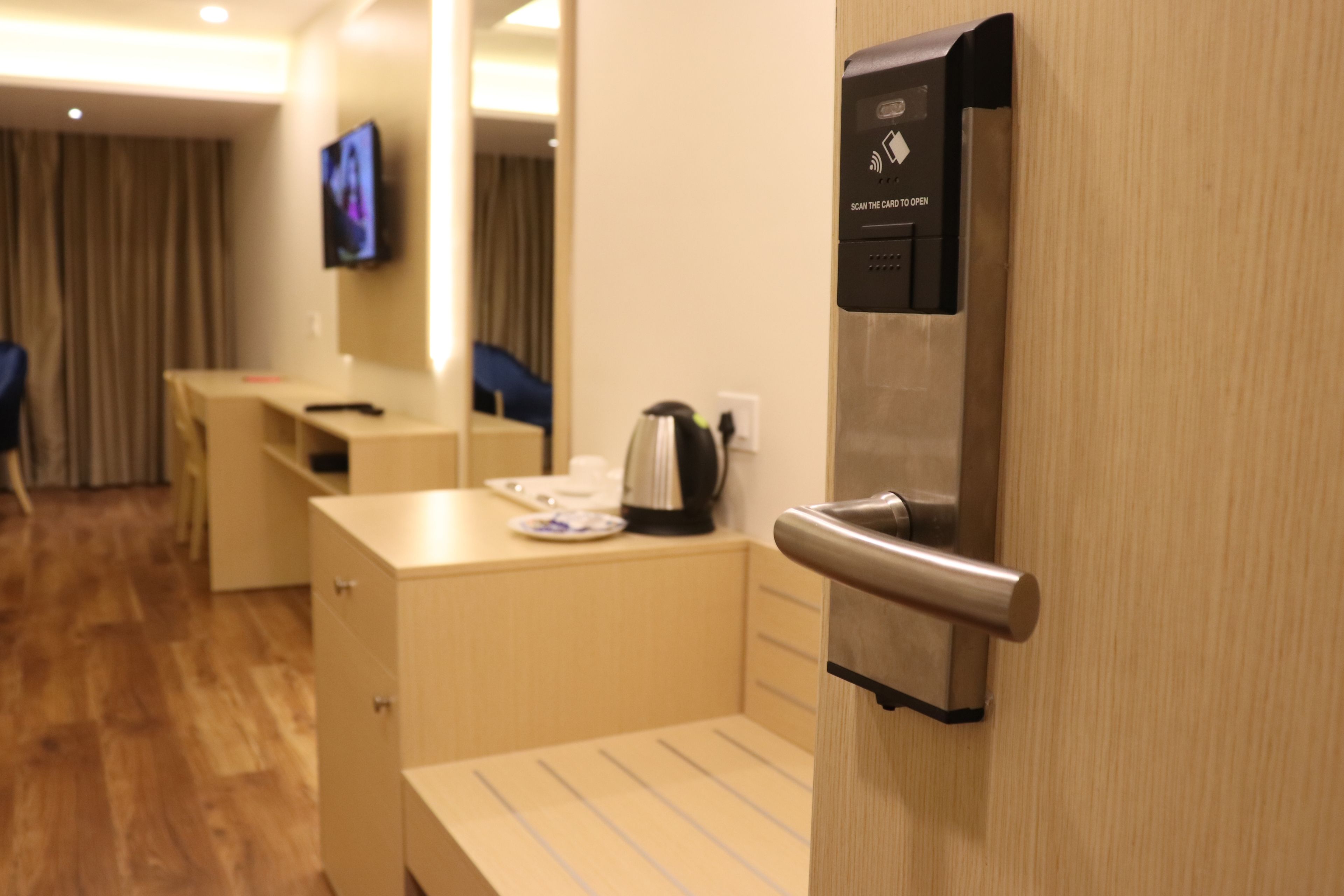 A hotel room with a wooden desk, a coffee maker, and a television mounted on the wall.