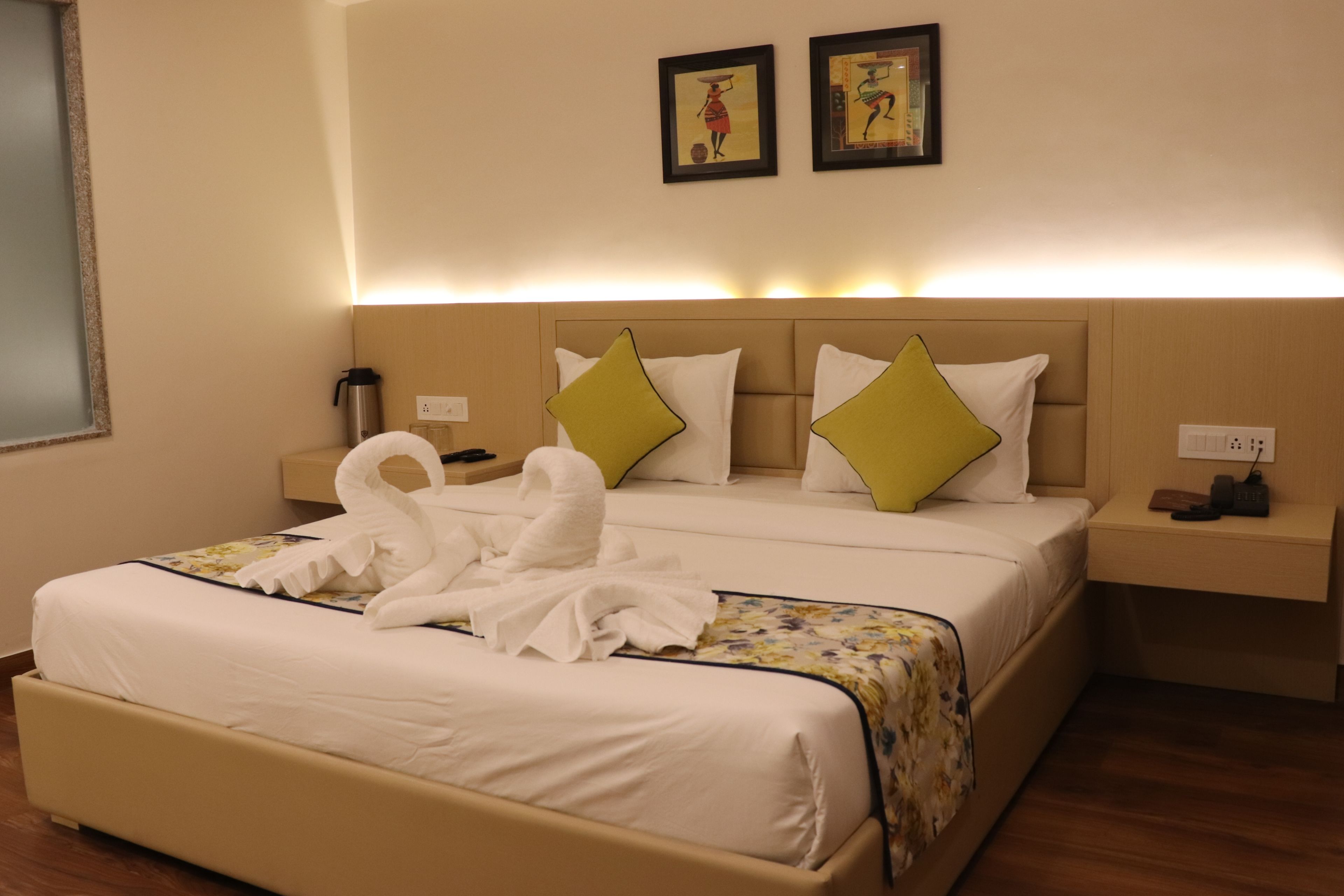 Habitación de hotel con una cama grande, dos almohadas, una mesita de noche y una obra de arte colgada en la pared.