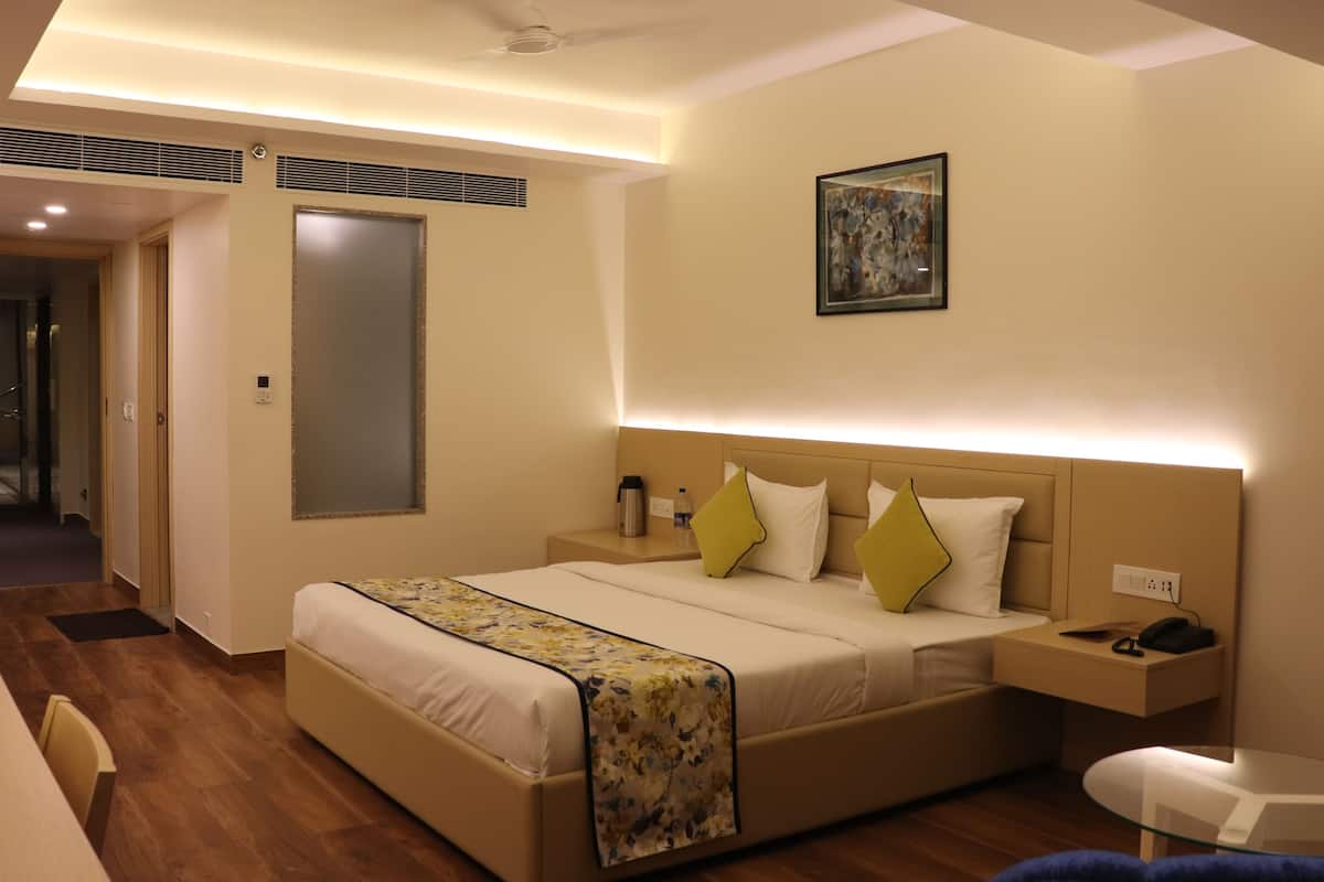 A hotel room with a bed, bedside table, and a small table with a chair.
