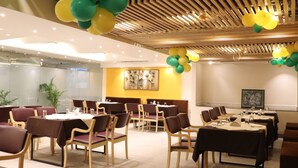 A conference room with tables and chairs, wooden ceiling, and balloons. - Hotel Le Amor (Kota)