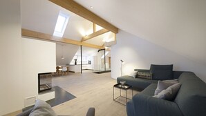A spacious loft apartment with high ceilings, a dining area, and a cozy living space with a sofa and a coffee table. - Haus Heimat 1883 (Garmisch-Partenkirchen)