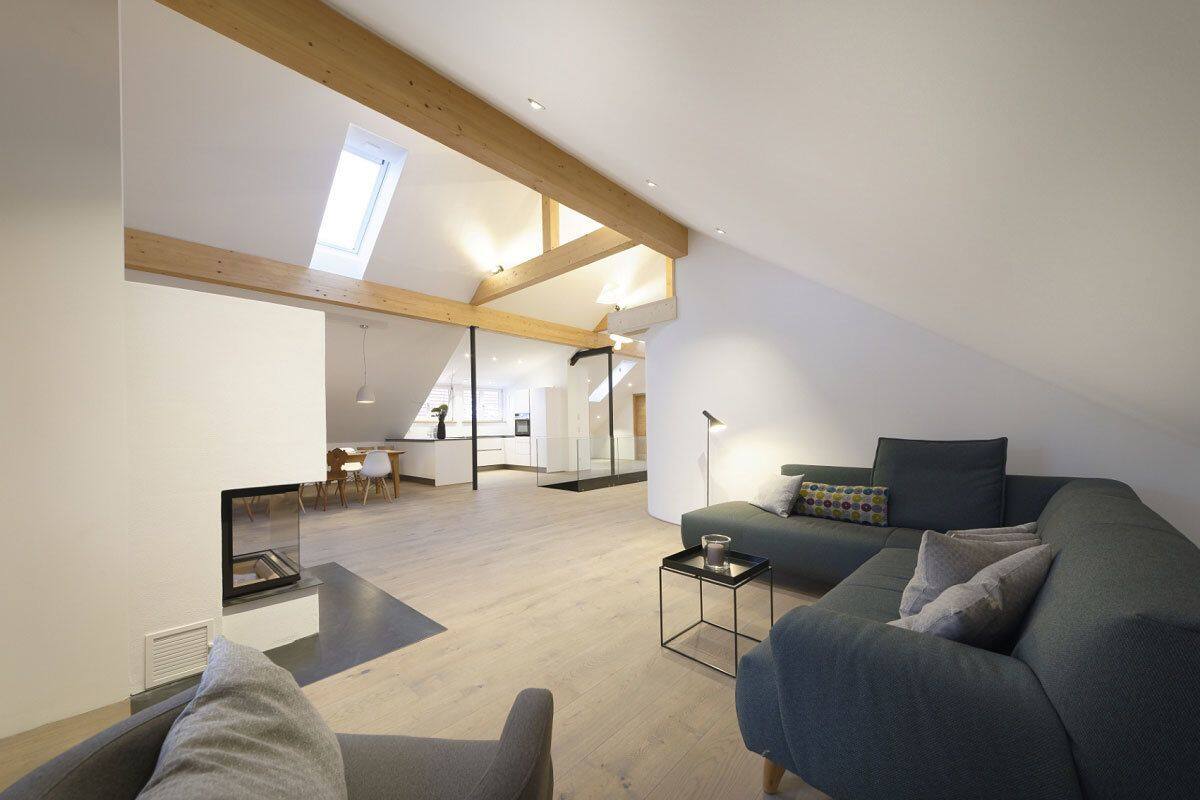 A spacious loft apartment with high ceilings, a dining area, and a cozy living space with a sofa and a coffee table.