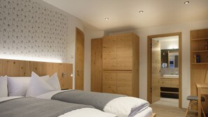 A modern bedroom with a large bed, wooden wardrobe, and a small desk with a chair. - Haus Heimat 1883 (Garmisch-Partenkirchen)