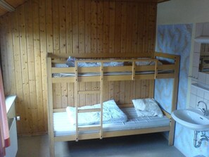 A bunk bed room with a wooden wall and a bathroom with a sink. - Jugendgästehaus Westkap Wangerooge (Wangerooge)