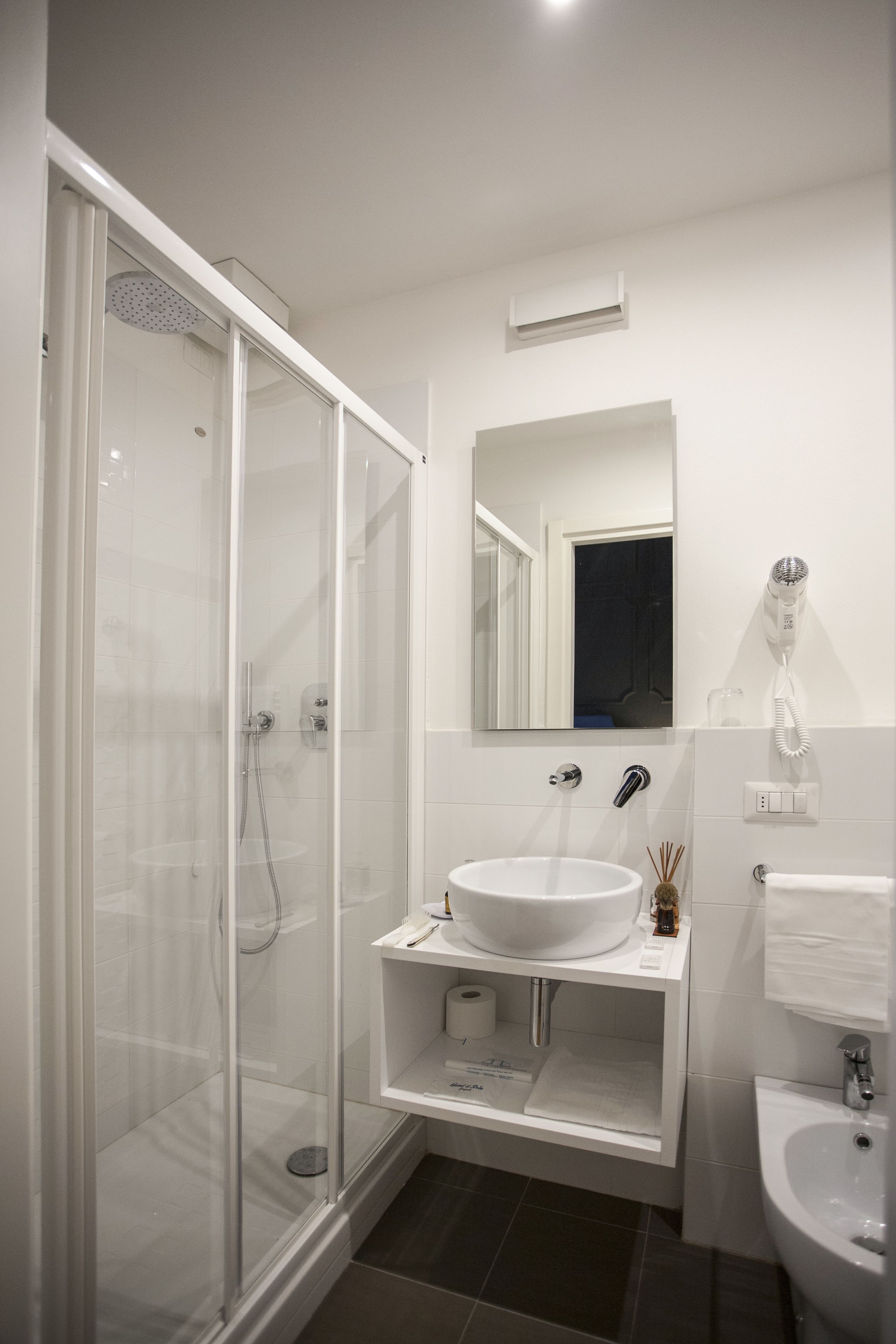 A modern bathroom with a glass-enclosed shower, a white sink, and a mirror above the sink.