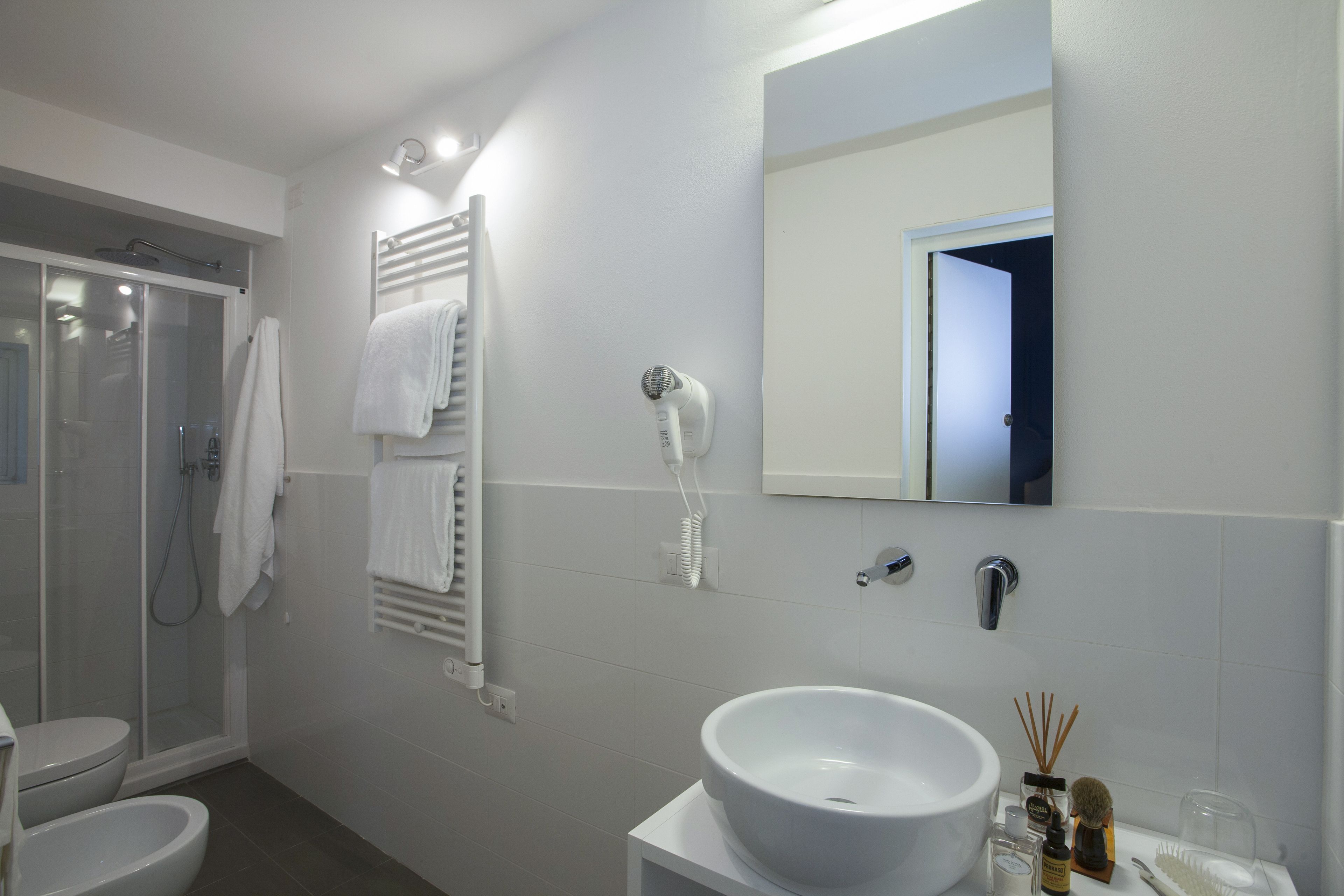 A modern bathroom with a glass shower enclosure, a white sink, a mirror, and a towel rack.