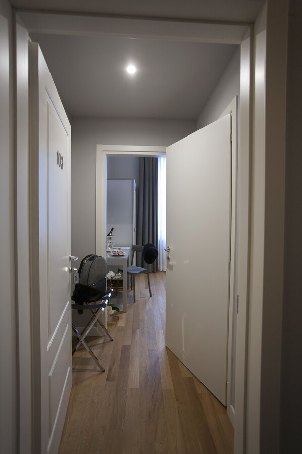 Un couloir étroit avec un plancher en bois, un bureau avec une chaise et une lampe.