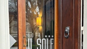 A hotel entrance with a wooden door, a glass window, and a red doormat. - Hotel Il Sole (Empoli)
