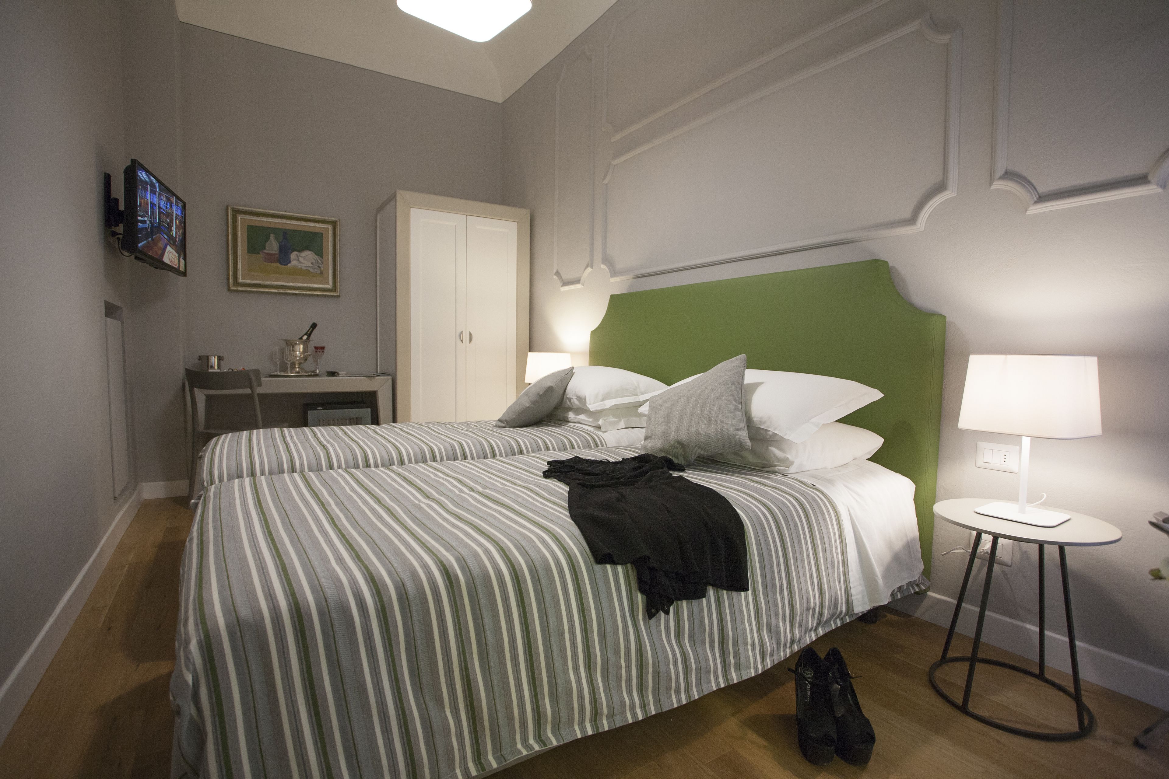 A neatly made bed with striped bedding, a bedside lamp, and a small table with a lamp.
