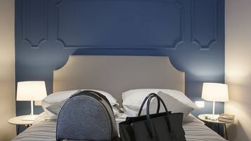 Quarto de hotel com uma cama, duas mesas de cabeceira, uma luminária em cada mesa e uma bolsa de mão preta sobre a cama.