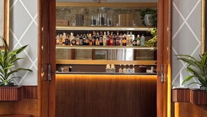 A bar area with a wooden counter, shelves with bottles, and potted plants. - Hotel Il Sole (Empoli)