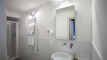 A modern bathroom with a white sink, a handheld hair dryer, a towel rack, and a shower.