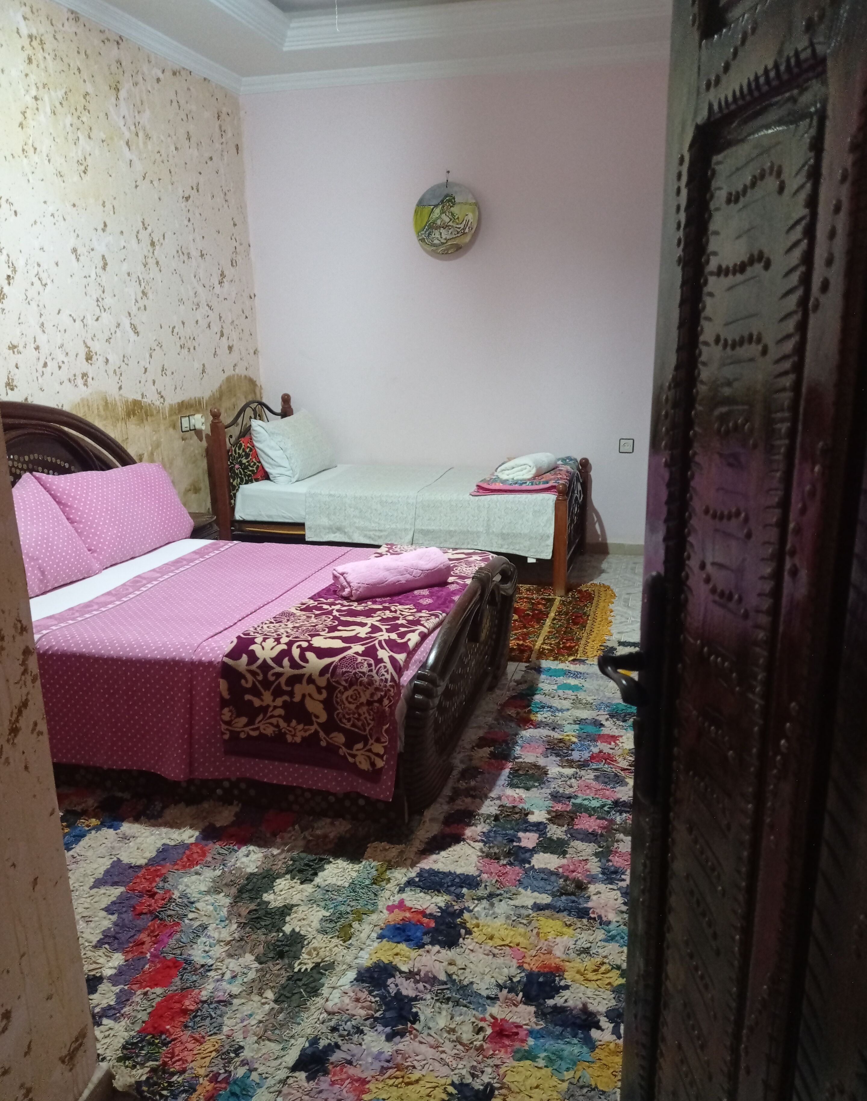 Una camera da letto con due letti, un tappeto colorato e un decoro a parete.