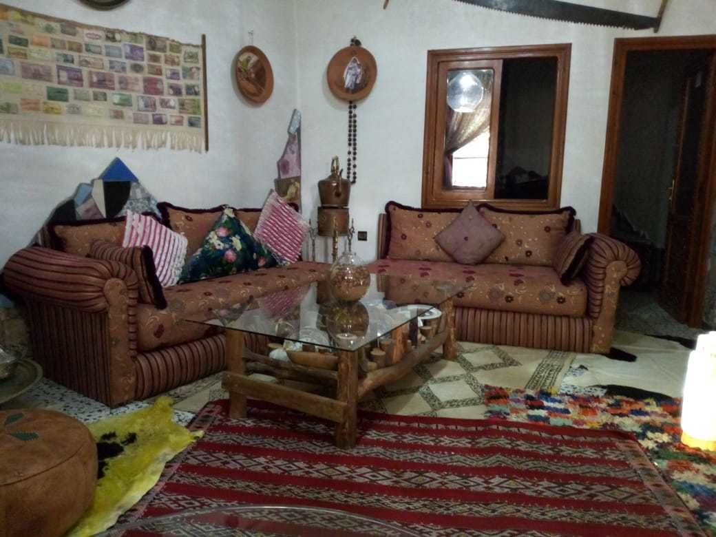 A living room with a sofa set, a glass coffee table, and a patterned rug.