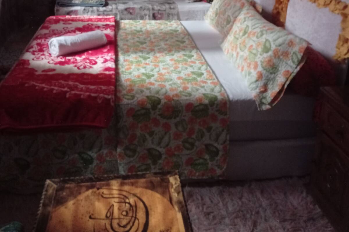 Une chambre à coucher avec un lit, une petite table et une fenêtre avec des rideaux.