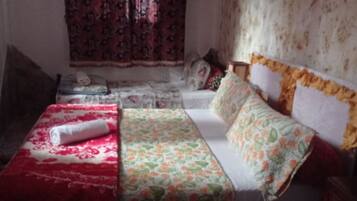 Een slaapkamer met een bed, een klein tafeltje en een raam met gordijnen.