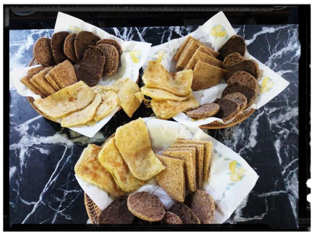 Una bandeja con varios panes planos y galletas sobre una superficie de mármol.