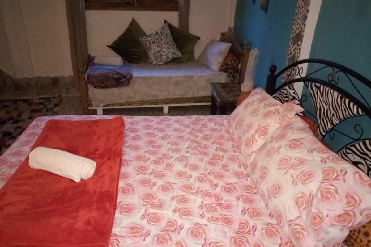 Un lit avec une couverture rouge et une couvre-lit à motifs floraux.