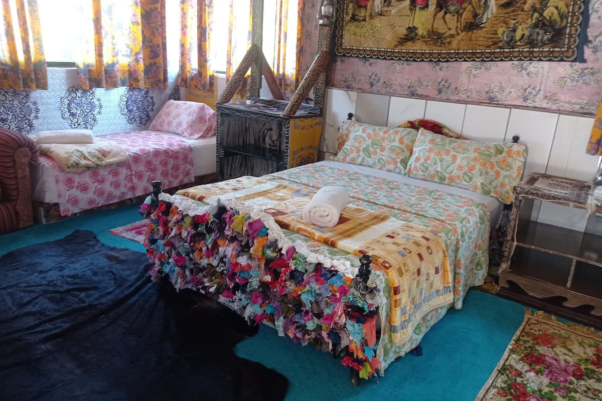 Une chambre à coucher avec un grand lit, deux tables de chevet, une chaise et une fenêtre avec des rideaux.