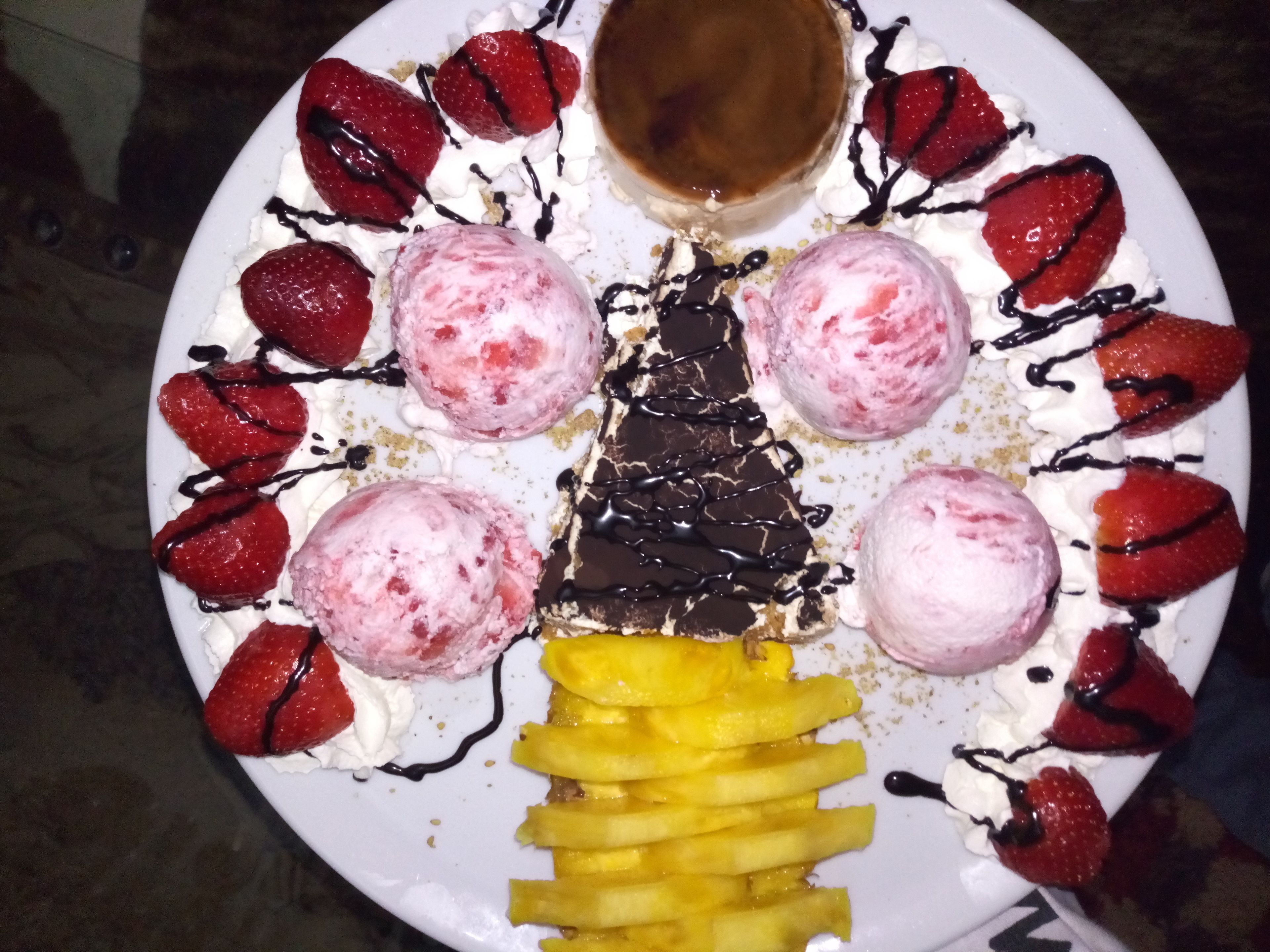 Ein Dessertteller mit Erdbeeren, Eis und einem Stück Schokolade.