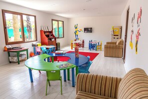 A children's playroom with colorful furniture, a large window, and a door with cartoon wall art. - Miarosa Incekum Beach (Alanya)