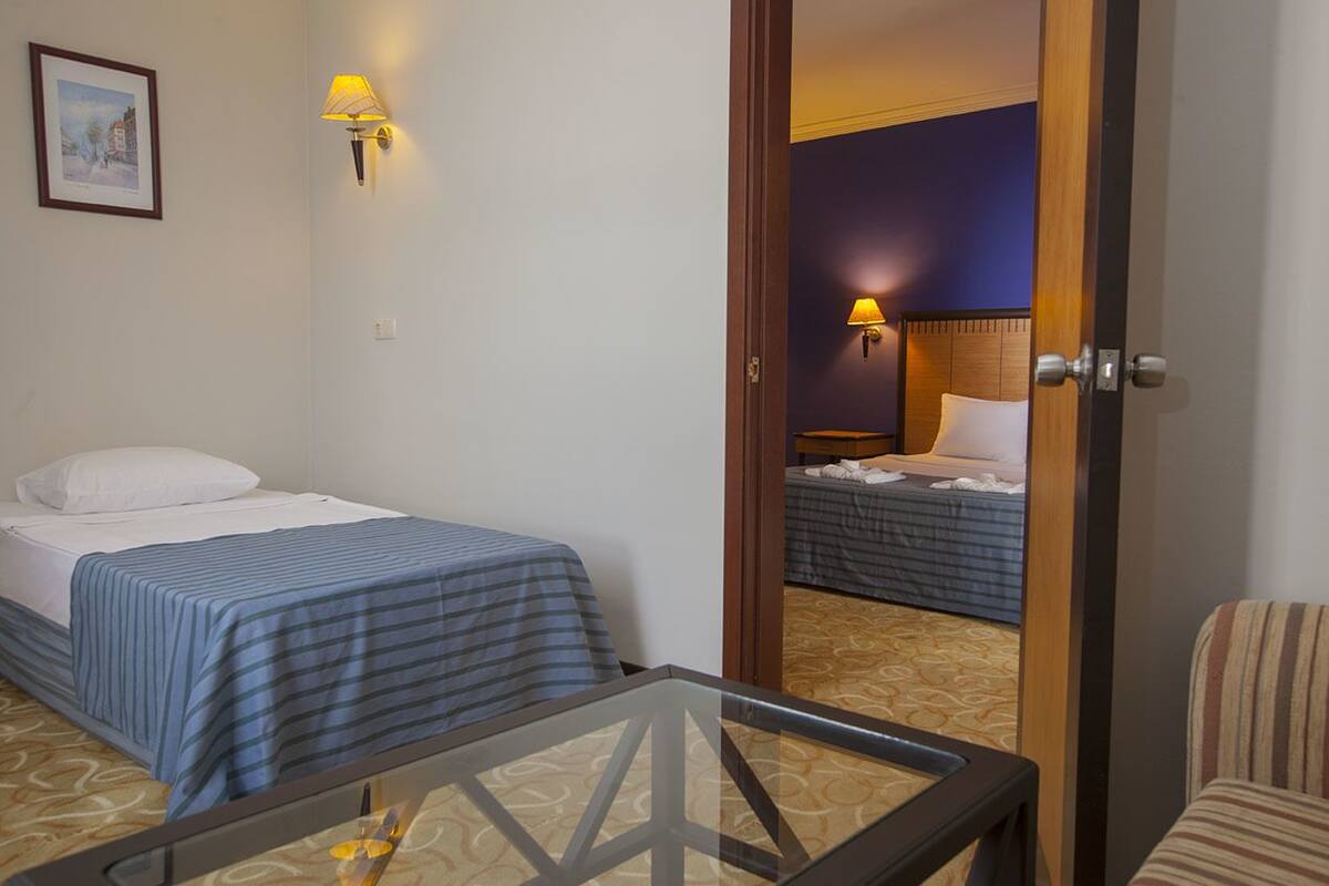 Una habitación de hotel con dos camas, una mesa de vidrio y una silla.