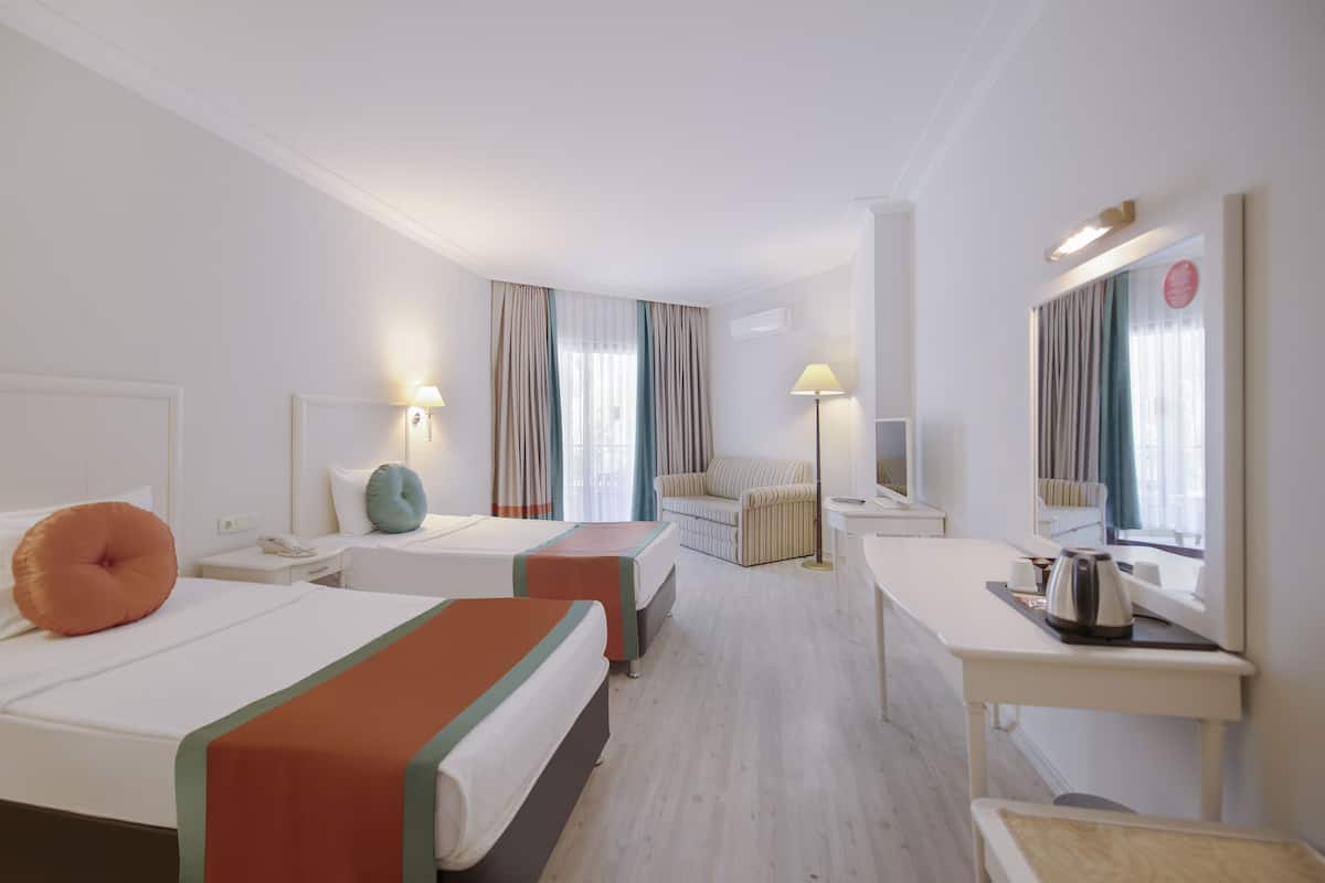 Una habitación de hotel con dos camas, un sofá, un escritorio y un espejo.