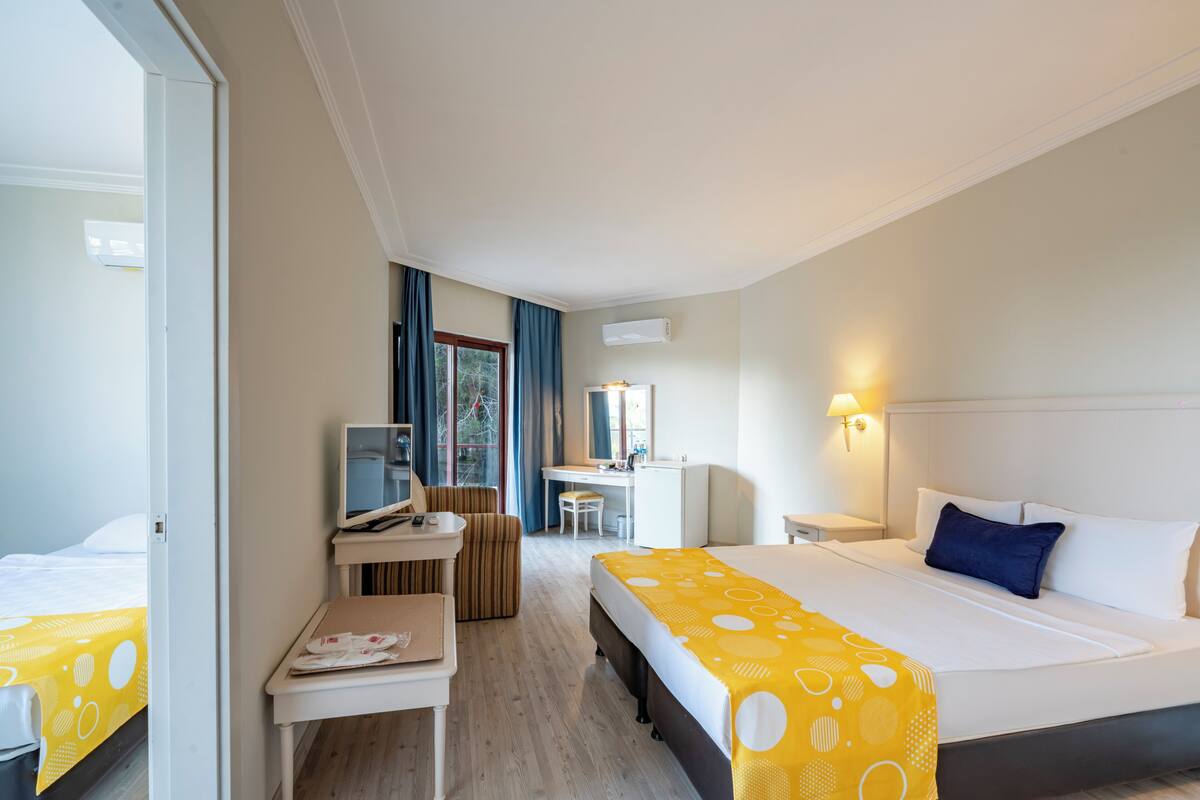Habitación de hotel con cama, escritorio, silla, mesita y espejo.