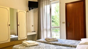 A hotel room with two beds, a wardrobe, a television, and a window with curtains. - Be Hotel Rimini (Rimini)