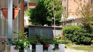 A courtyard with a white wooden fence, potted plants, and a brick pathway. - Be Hotel Rimini (Rimini)
