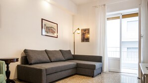 Un salon moderne avec un canapé d’angle gris, une petite table et une lampe sur pied.
