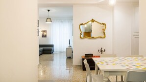 Un espace repas comprenant une table, des chaises, un miroir et un lustre.