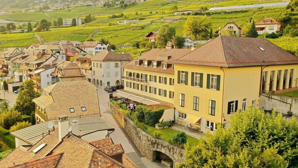 Una hilera de edificios tradicionales de estilo europeo, con tejados inclinados, un muro de piedra y una calle pavimentada.
