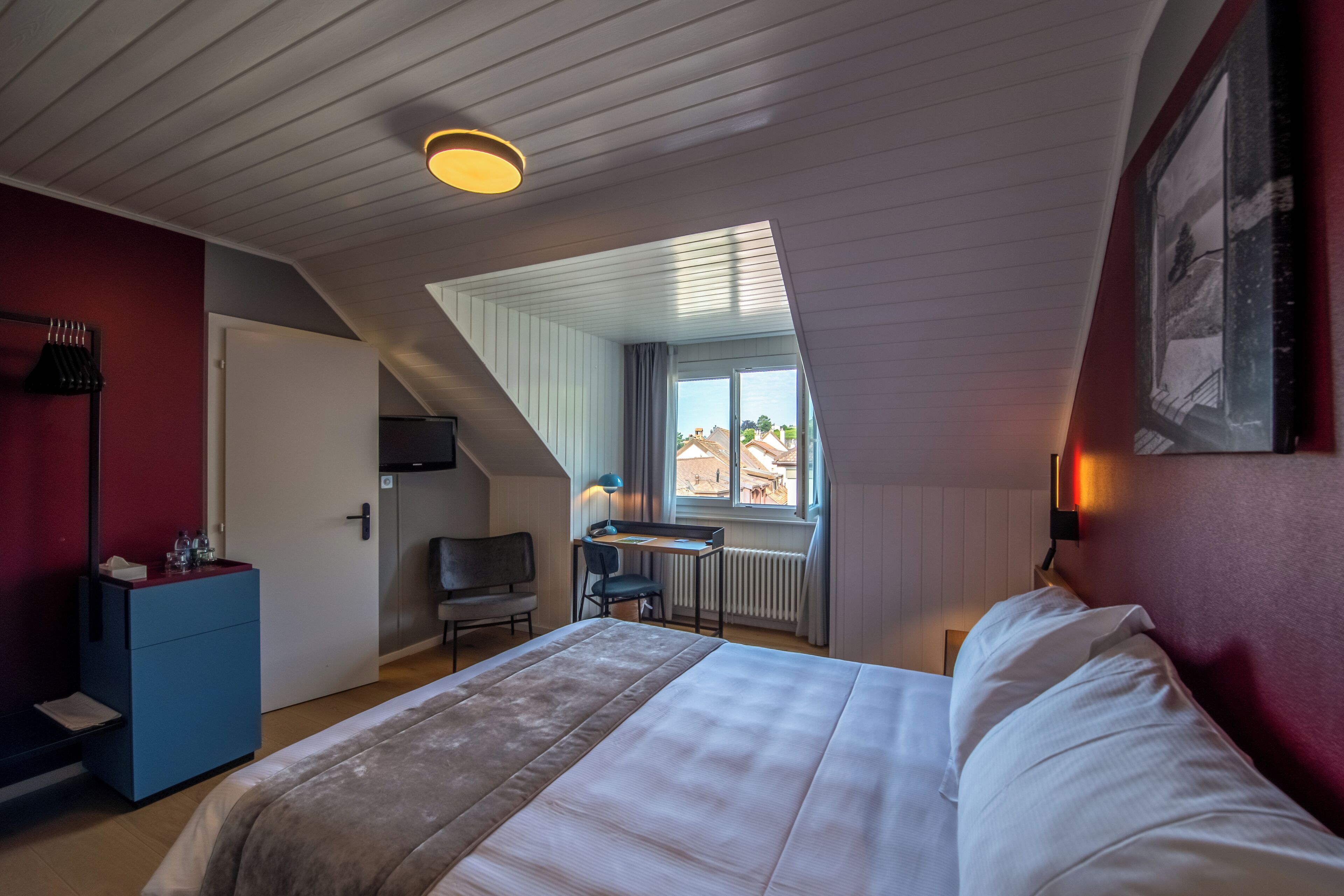 Une chambre à coucher comprenant un lit, un bureau, une chaise et donnant sur l’extérieur.