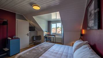 Une chambre à coucher comprenant un lit, un bureau, une chaise et donnant sur l’extérieur.