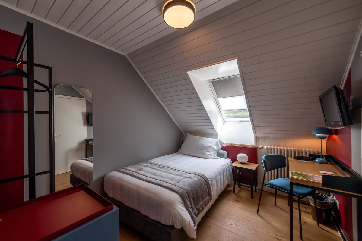 Un dormitorio compacto con zona de dormir elevada, un escritorio y una silla.