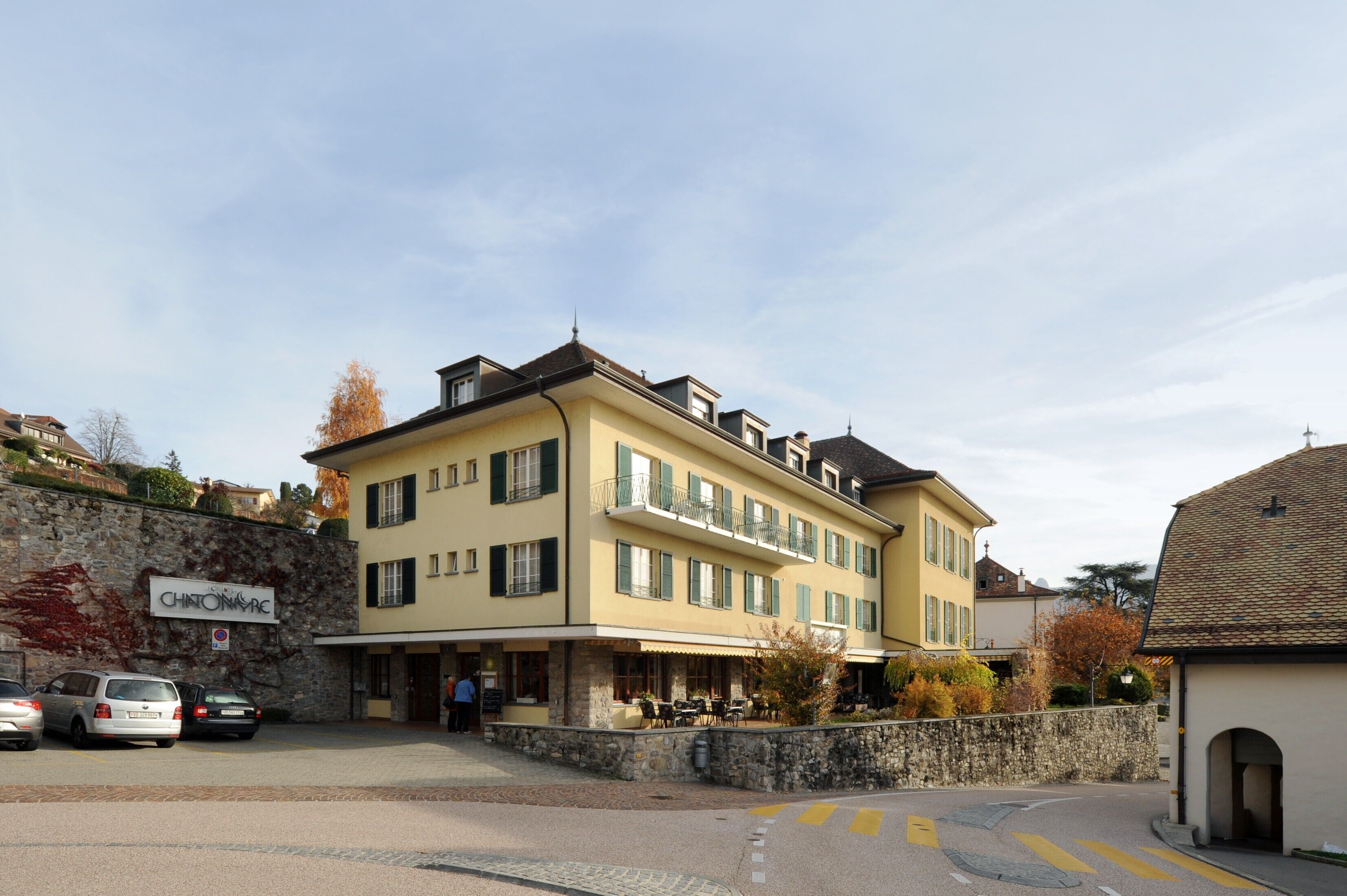 A multi-story hotel with a stone facade, balconies, and outdoor seating.
