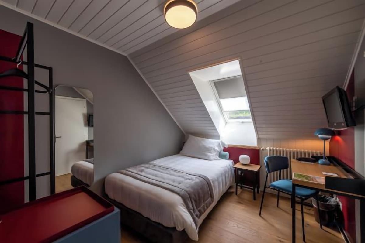 A bedroom with a bunk bed, a desk, a chair, and a television.