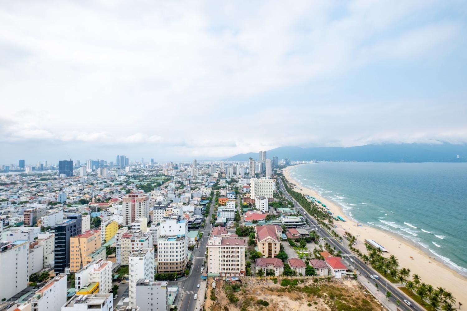 Un paysage urbain côtier avec une plage et une zone urbaine densément peuplée.