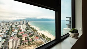 Paisaje urbano con vista al mar a través de una ventana, incluyendo edificios y una carretera.