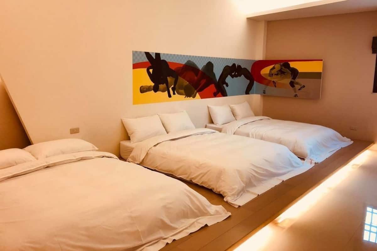A hotel room with two beds, a large abstract painting on the wall, and a window providing natural light.