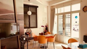 Une cuisine moderne équipée d’une télévision, d’un ventilateur et d’un coin repas avec des chaises orange.