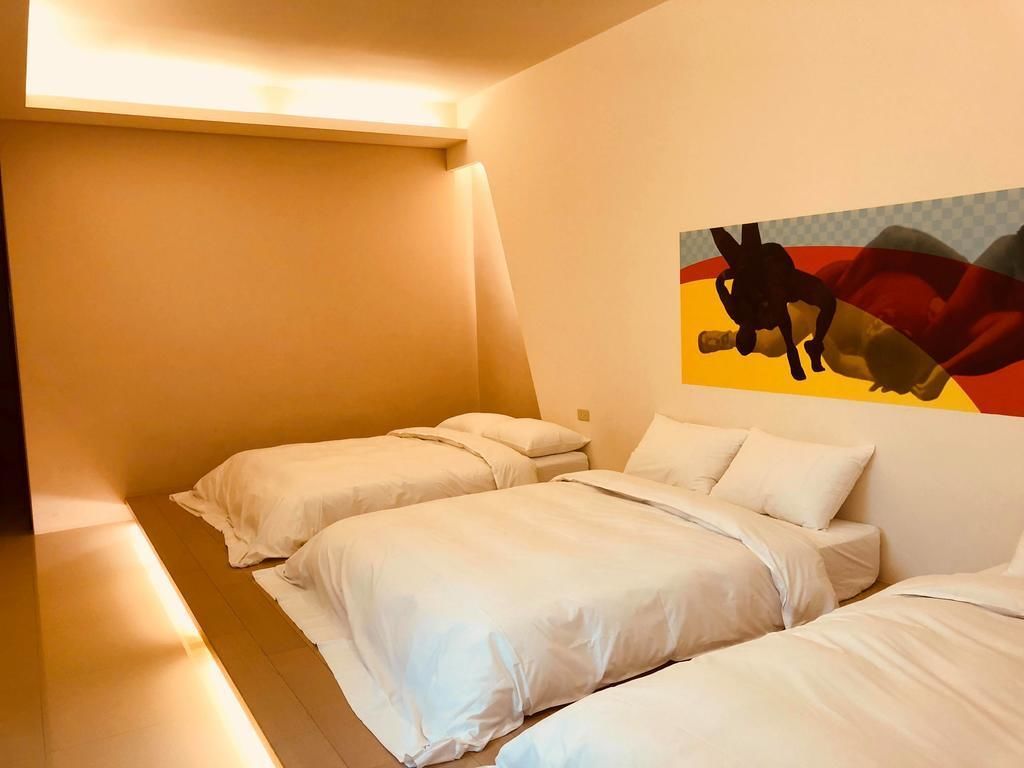 Une chambre d’hôtel avec deux lits simples, une œuvre d’art accrochée au mur et un plafond en pente.