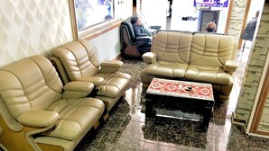 Un espacio de descanso con dos sofás, una mesa de centro, un sillón de masaje y piso de baldosas.